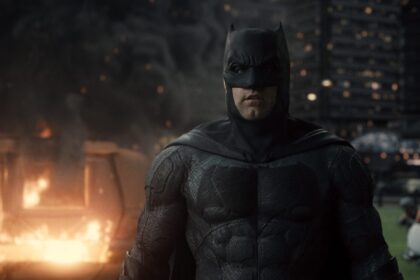 Ben Affleck's Batman in a dark, gritty scene with fire and destruction, embodying action and drama, not horror.