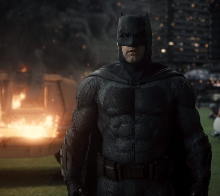 Ben Affleck's Batman in a dark, gritty scene with fire and destruction, embodying action and drama, not horror.