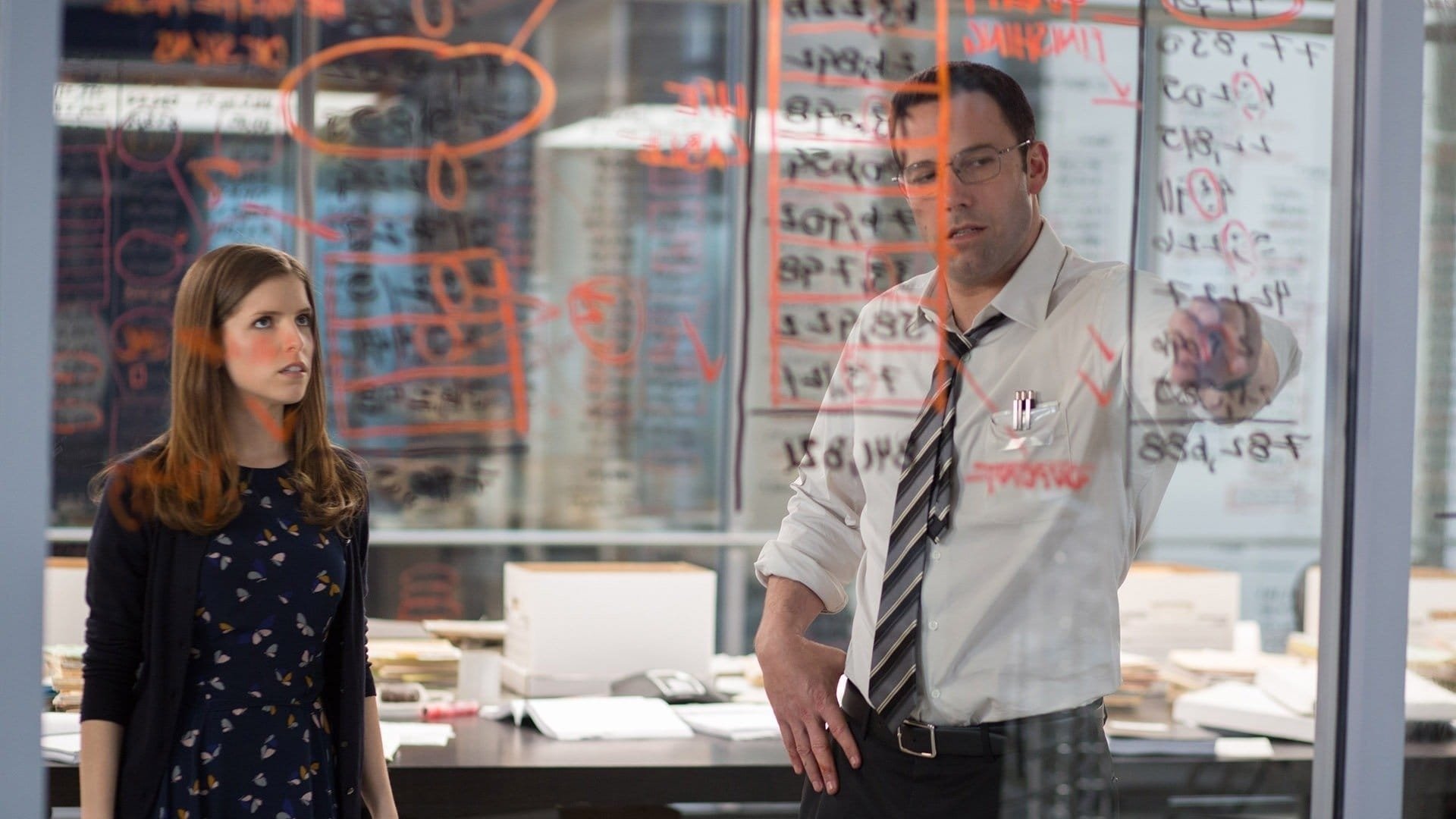 Movie still from The Accountant (2016). Christian Wolff (Ben Affleck) and Dana Cummings (Anna Kendrick) intensely focused on papers, working on the Living Robotics audit in The Accountant.